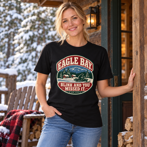 Woman wearing Eagle Bay Blink and You Missed It snowmobile tee on a snowy cabin porch