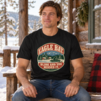 Man seated on a cabin bench wearing Eagle Bay snowmobile tee