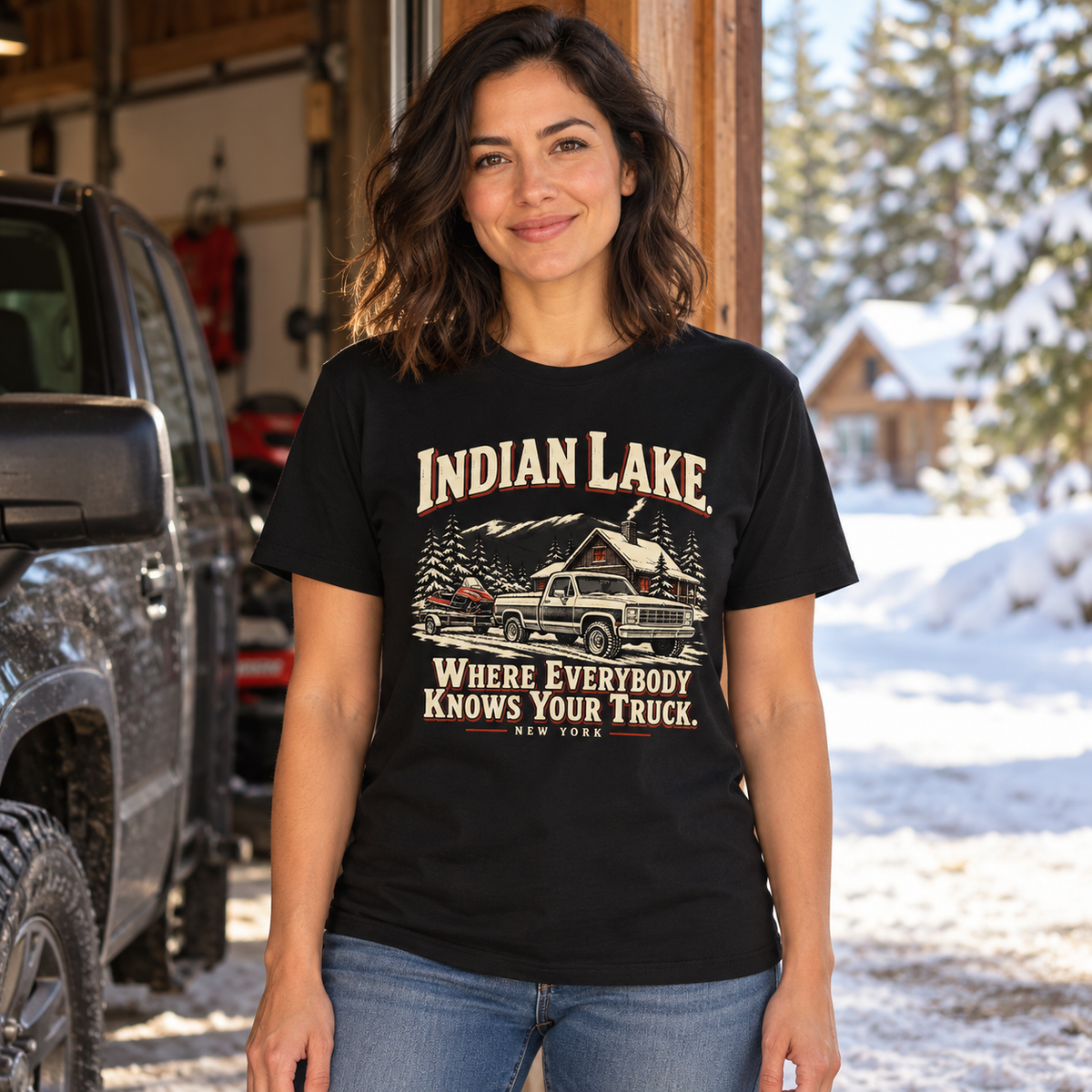 Woman wearing Indian Lake Where Everybody Knows Your Truck tee beside a pickup