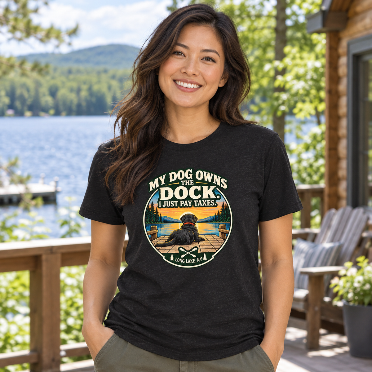 AI-generated lifestyle mockup of a woman wearing the black heather My Dog Owns the Dock tee beside a lake.