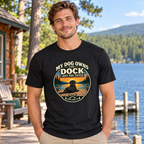 AI-generated lifestyle mockup of a man wearing the black heather My Dog Owns the Dock tee at a lakeside camp.
